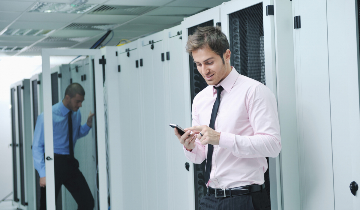 young business man computer science engeneer talking by cellphone at network datacenter server room asking  for help and fast solutions and services